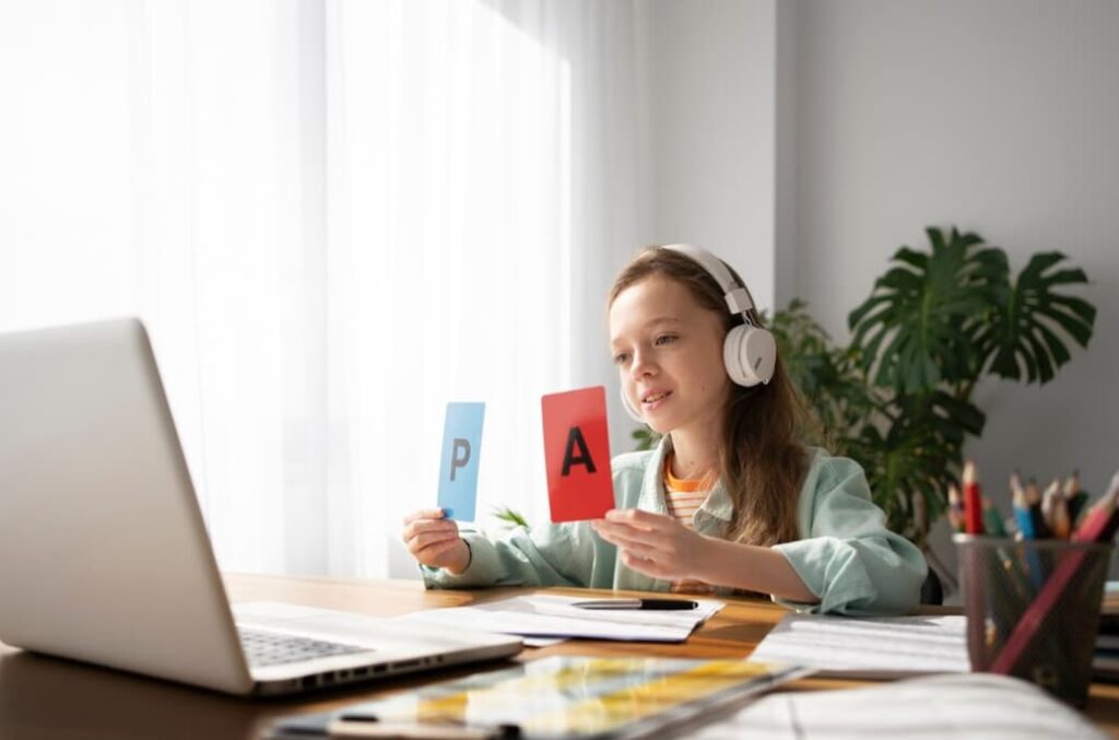 Ragazza con cuffie tiene in mano le lettere "P" e "A" davanti a un laptop